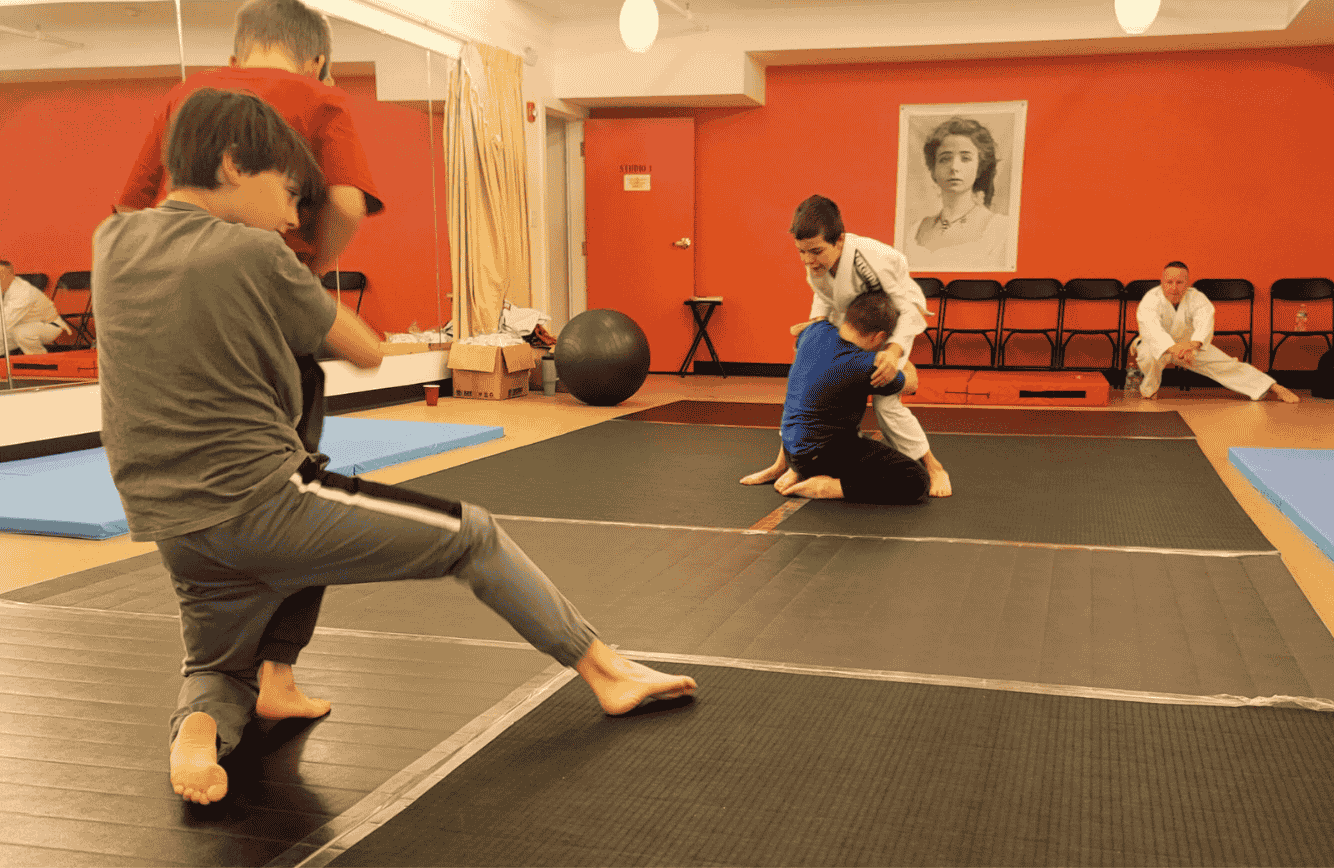 A coach helping a white belt tie the gi